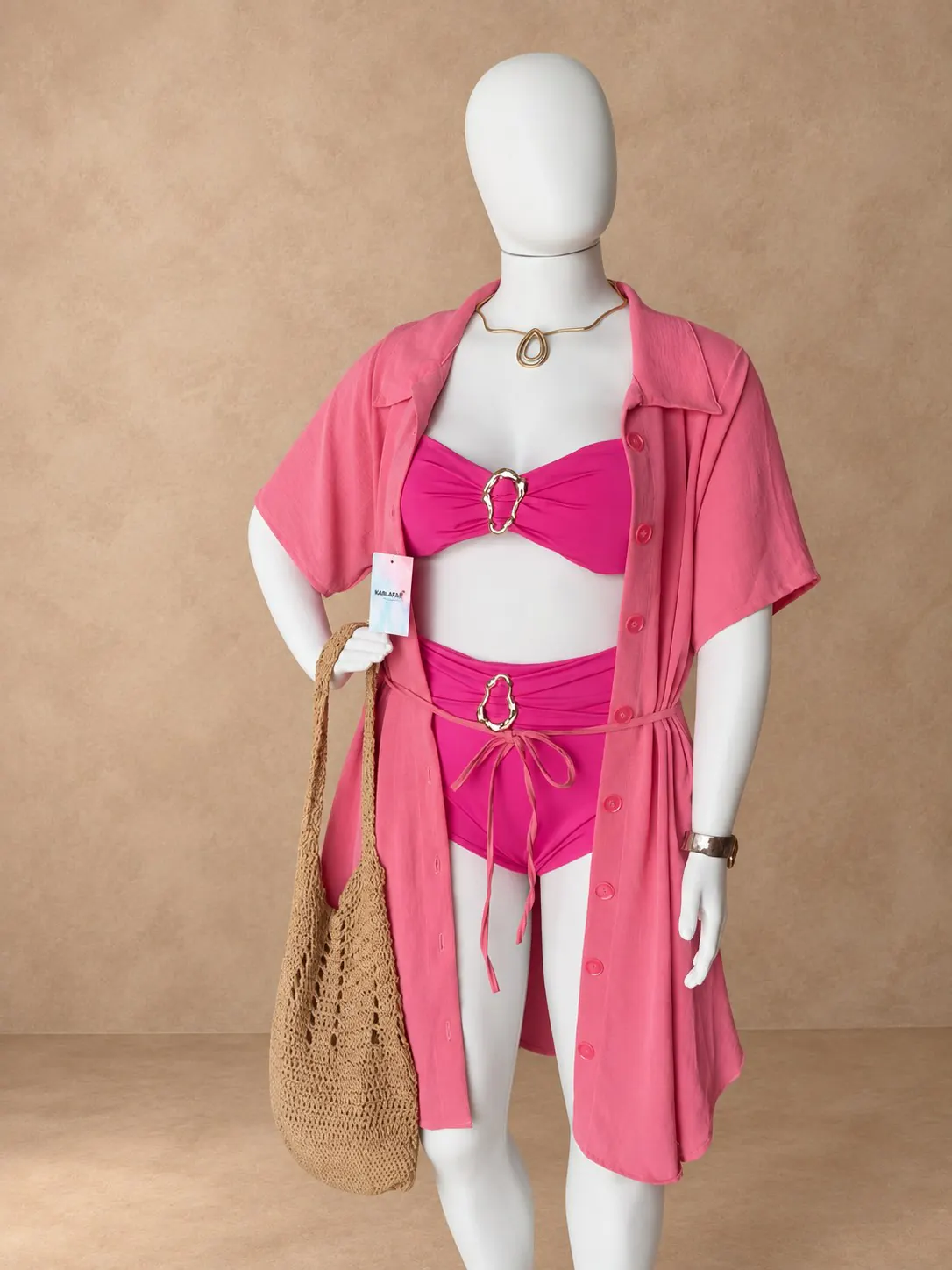 Manequim com biquíni rosa de detalhes metálicos, saída de praia rosa e bolsa de palha