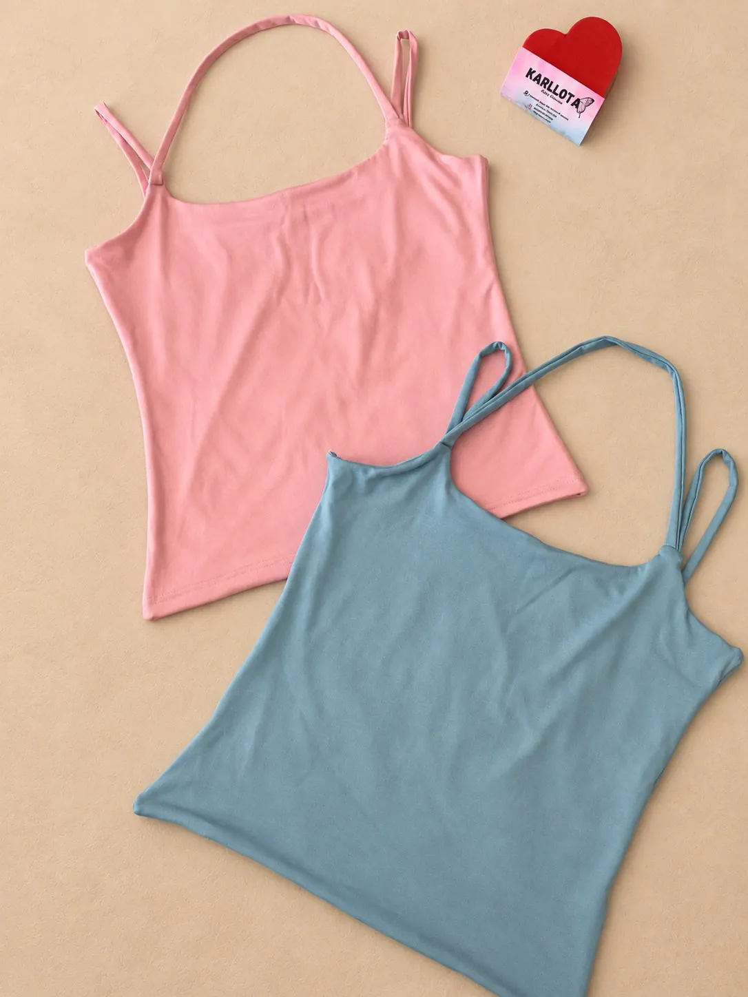 Blusa modinha Slim nas cores rosa e azul, apresentada sobre fundo areia.