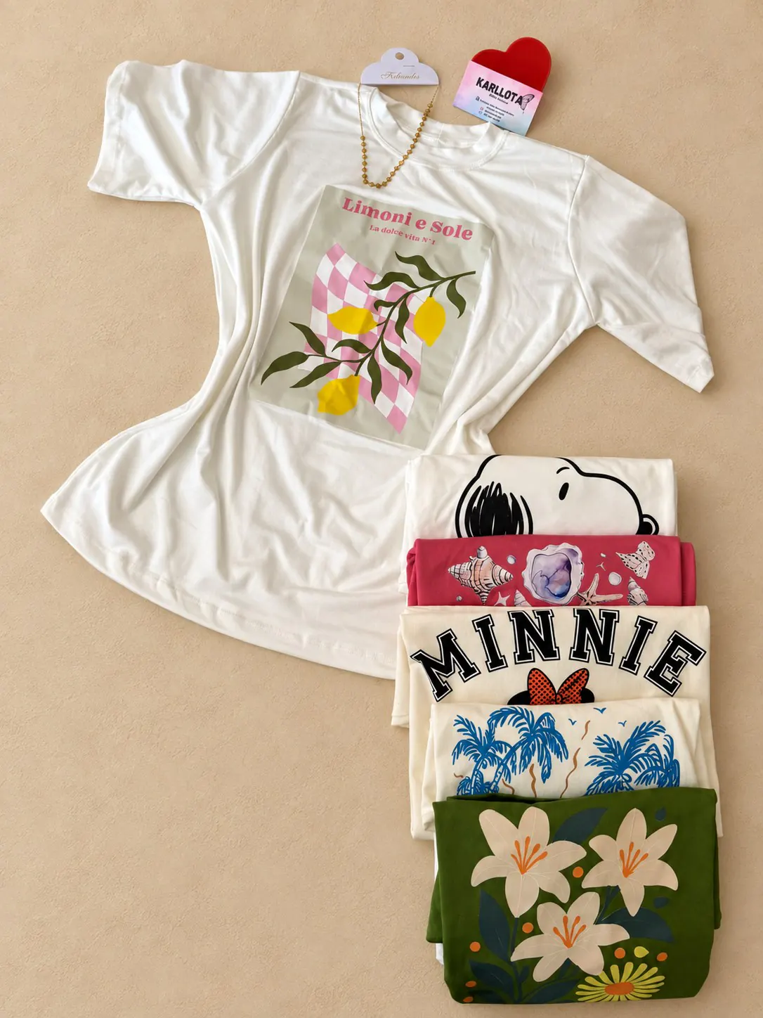 T-shirt Slim branca com estampa de limões, acompanhada de outras opções estampadas, sobre fundo areia.