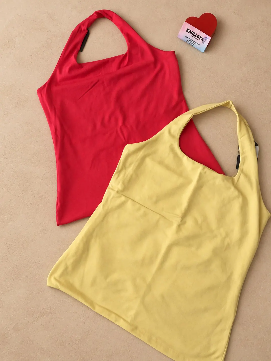 Blusa modinha Plus nas cores vermelha e amarela, apresentada sobre fundo areia.