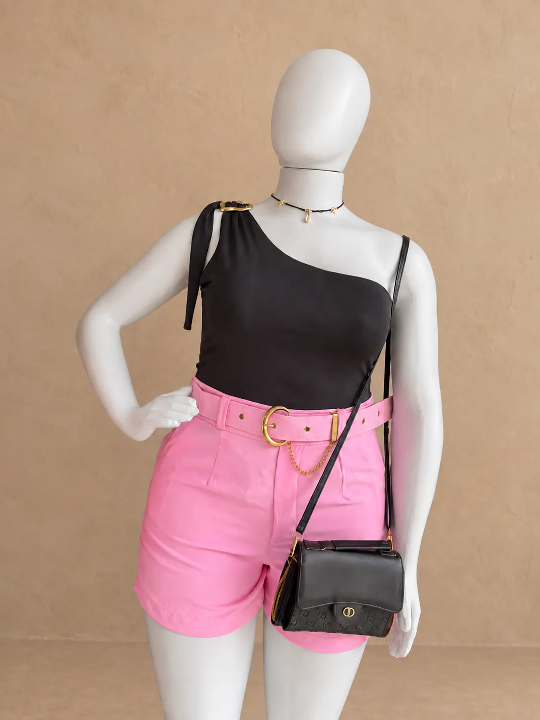 Cropped preto de um ombro só com short rosa e cinto em manequim único.