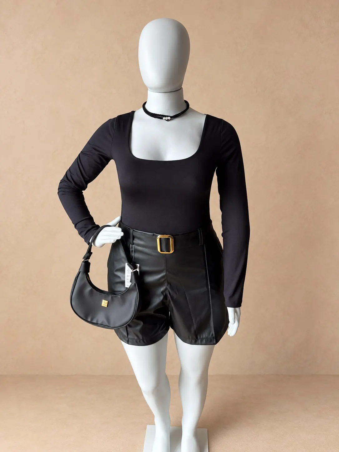 Peça preta de mangas longas com shorts preto e cinto.