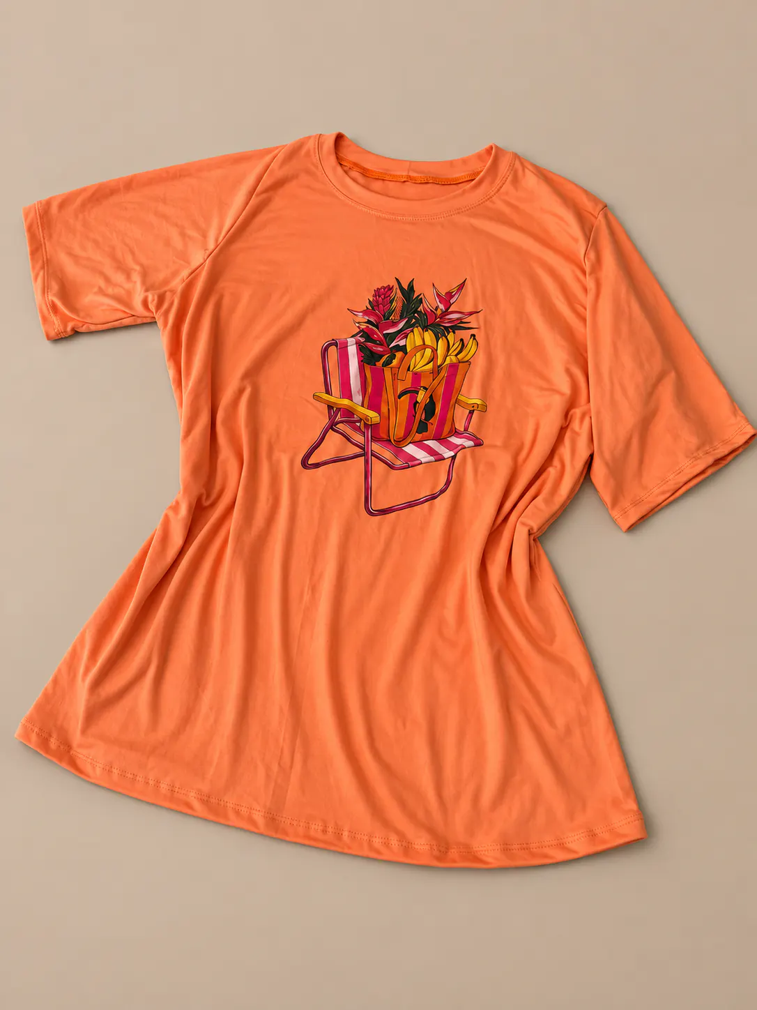 T-shirt Plus laranja com estampa tropical, apresentada sobre fundo de estúdio areia.