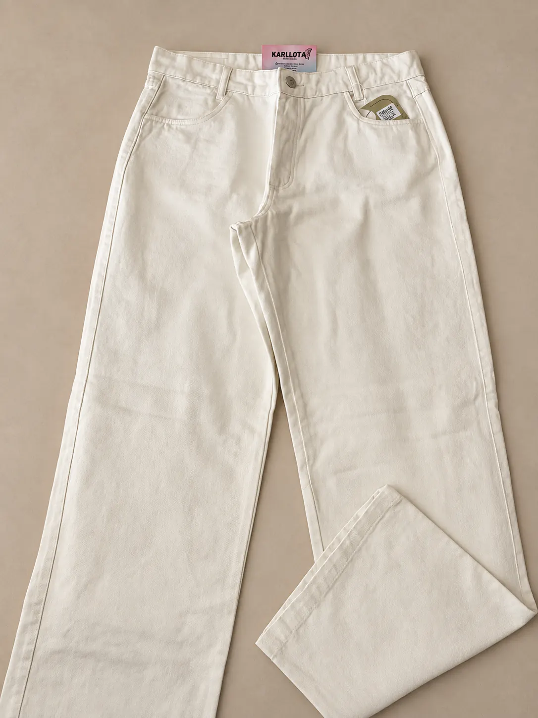 Calça Wide Leg Off White em foto de detalhe sobre fundo areia.