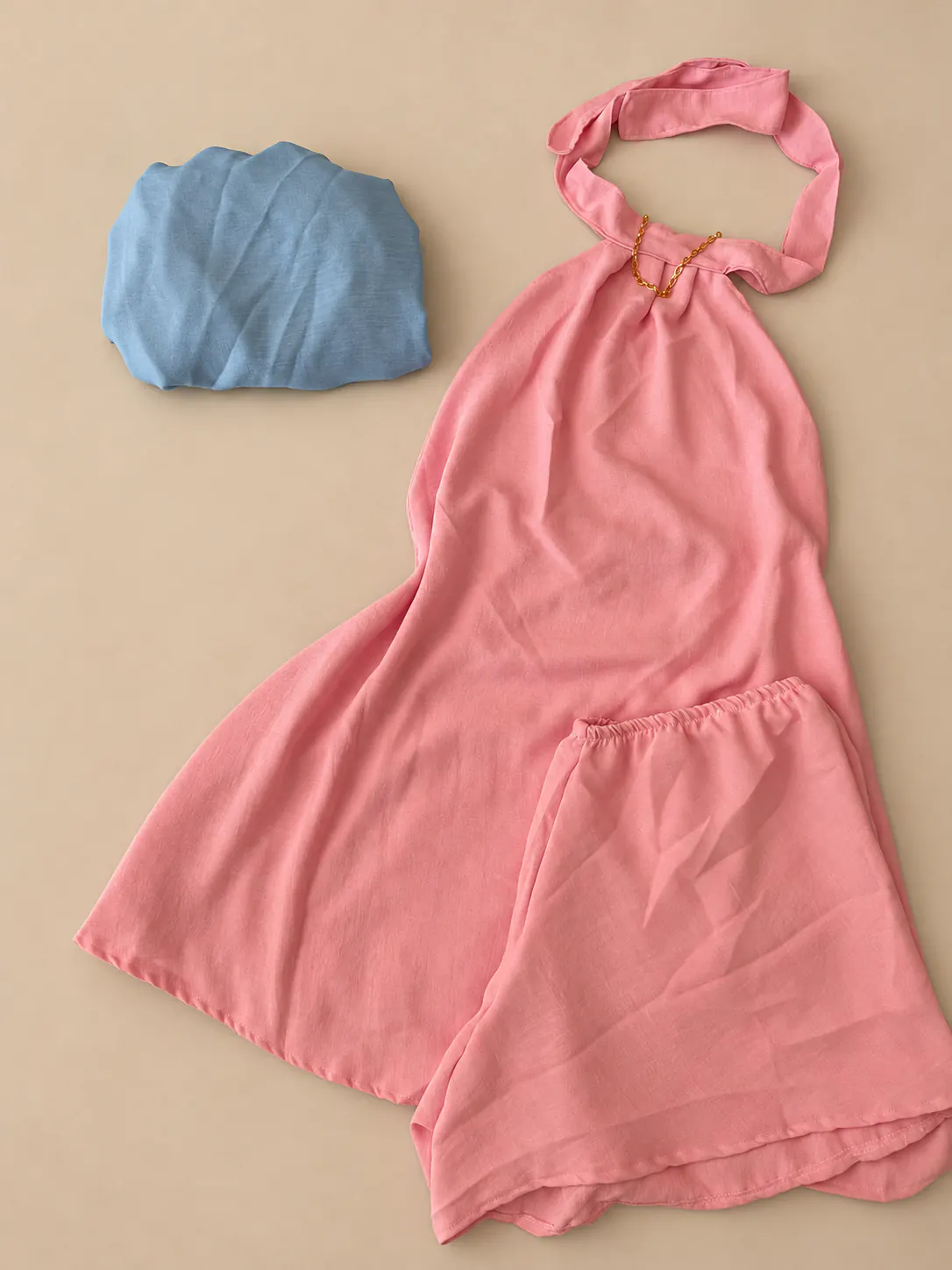 Conjunto rosa de blusa frente única e short acompanhado de top azul.